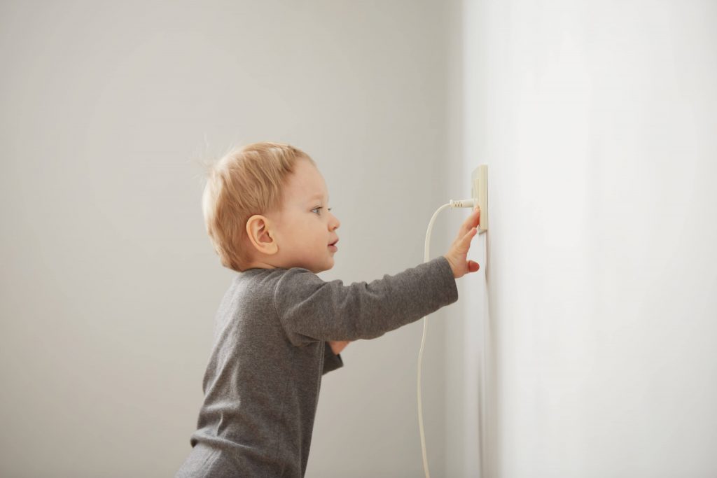 Curious little boy playing with electric plugin